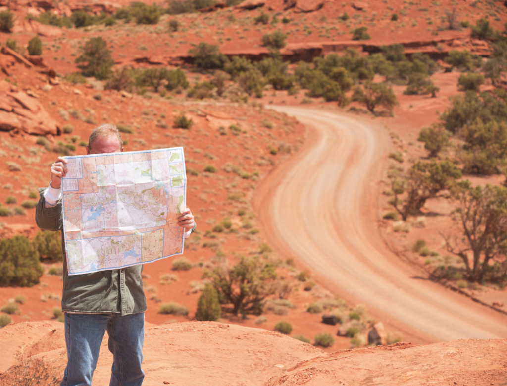 Man looking at a map looking for directions on a desert highway
